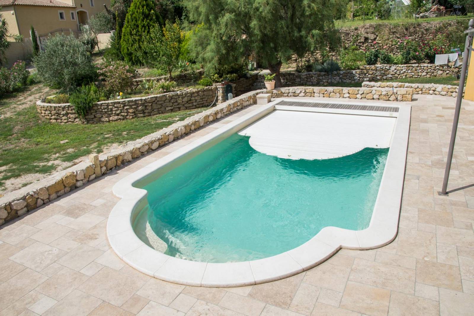 PISCINE COQUE POLYESTER À FOND PLAT AVEC COUVERTURE AUTOMATIQUE CAILLEBOTIS BOIS ET BANQUETTE MODÈLE MALDIVES