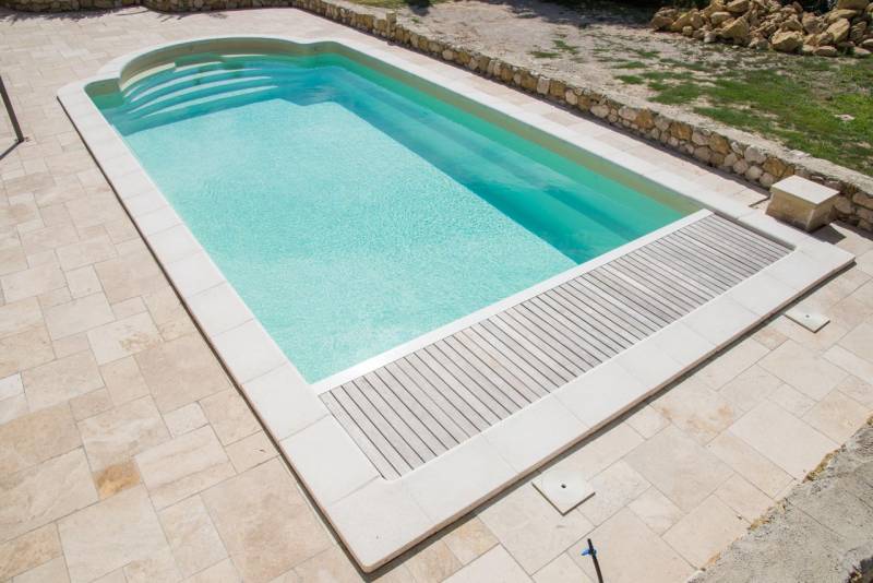 PISCINE COQUE POLYESTER À FOND PLAT AVEC COUVERTURE AUTOMATIQUE CAILLEBOTIS BOIS ET BANQUETTE MODÈLE MALDIVES