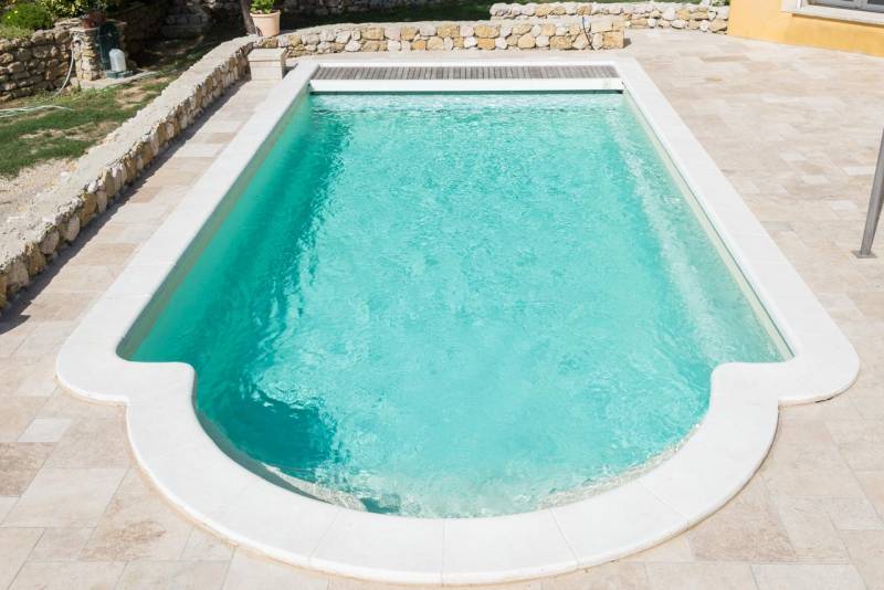 PISCINE COQUE POLYESTER À FOND PLAT AVEC COUVERTURE AUTOMATIQUE CAILLEBOTIS BOIS ET BANQUETTE MODÈLE MALDIVES
