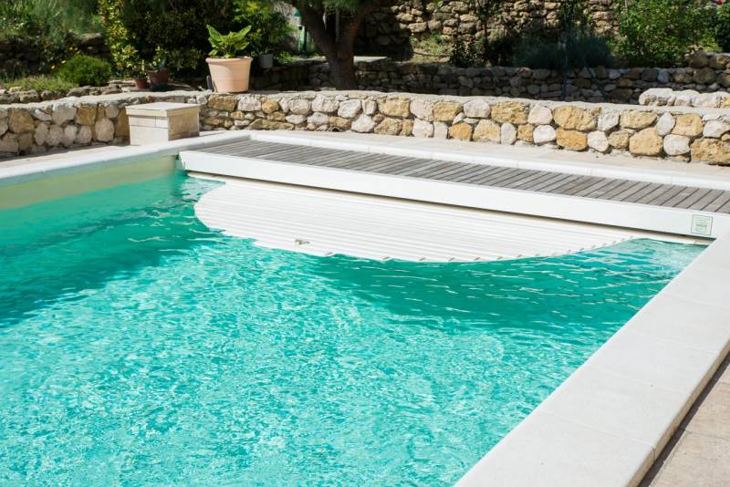 PISCINE COQUE POLYESTER À FOND PLAT AVEC COUVERTURE AUTOMATIQUE CAILLEBOTIS BOIS ET BANQUETTE MODÈLE MALDIVES